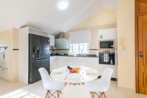 eine Küche mit einem weißen Tisch und weißen Stühlen in der Unterkunft Branco's Apartment by GALMI in Ponta do Sol