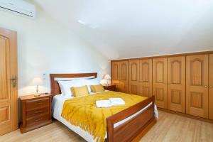 1 dormitorio con 1 cama grande con manta amarilla en Branco's Apartment by GALMI en Ponta do Sol