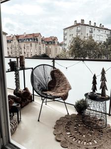 a balcony with a chair and a view of a city at Le cocon Blånc Metz -T2 cosy avec parking privé & balcon - Gare, Nouvelle Ville in Metz