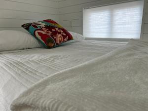 Cama blanca con almohada y ventana en Entirely Private Tiny Home - 1 Mile to UF, en Gainesville