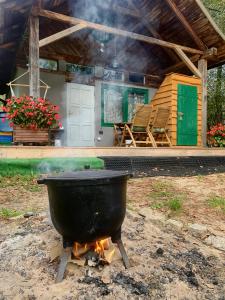 a large pot on a fire in front of a house at Agroturystyka Leśny Zakątek - Domek z sauną in Ożarów