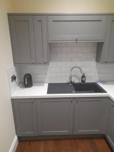 a kitchen with white cabinets and a sink at Kirkcudbright Holiday Apartments - Apartment D in Kirkcudbright