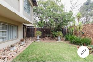 a backyard of a house with a fence and a garden at Jewel of Jozi in Edenvale
