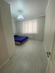 a bedroom with a blue bed and a wooden floor at 2х комнатная квартира в элитном ЖК Альтаир в центре города in Aktobe