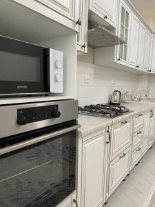 a kitchen with white cabinets and a black microwave at 2х комнатная квартира в элитном ЖК Альтаир в центре города in Aktobe +26 photos