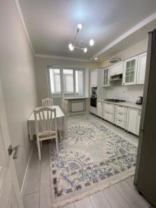 a kitchen with white cabinets and a table and a chair at 2х комнатная квартира в элитном ЖК Альтаир в центре города in Aktobe