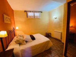 um quarto com uma cama com lençóis brancos e almofadas em Muley Hacén em Capileira