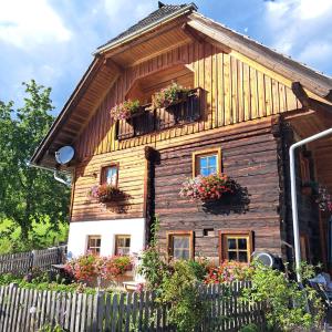 ein Holzhaus mit Blumenkästen an den Fenstern in der Unterkunft Ferienwohnung Familie Sigl - Rotlechner in Sankt Peter am Kammersberg