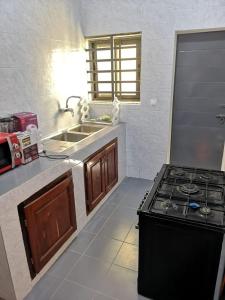 Il comprend une cuisine équipée d'une cuisinière et d'un évier. dans l'établissement TAYKI, à Cotonou