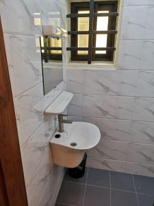 La salle de bains blanche est pourvue d'un lavabo et d'un miroir. dans l'établissement TAYKI, à Cotonou