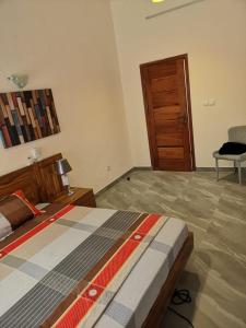 - une chambre avec un lit et une porte en bois dans l'établissement TAYKI, à Cotonou