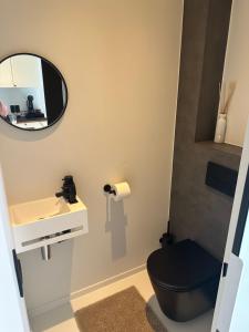 a bathroom with a black toilet and a mirror at Antwerp West Side, TERRACE in Zwijndrecht