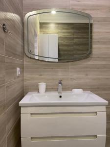 La salle de bains est pourvue d'un lavabo blanc et d'un miroir. dans l'établissement 2х комнатная квартира в элитном ЖК Альтаир в центре города, à Aqtöbe