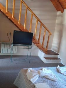 een kamer met een bed, een televisie en een trap bij Hotel Kallfu by Nordic in Caviahue