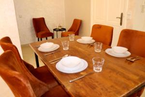 a wooden table with plates and glasses on it at Magnifique Appartement Marrakech - 2 Chambre 2 Salle de Bains in Marrakech