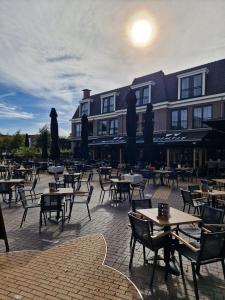 un patio avec des tables et des chaises en face d'un bâtiment dans l'établissement B&B Nature & U, à Voorthuizen