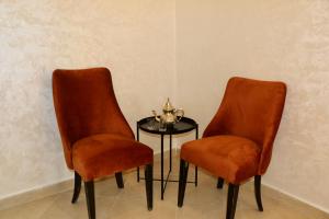 Duas cadeiras cor-de-laranja e uma mesa com uma tigela. em Magnifique Appartement Marrakech - 2 Chambre 2 Salle de Bains em Marrakech