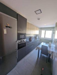 a kitchen with a table and a stainless steel refrigerator at Piso completo y moderno, Burgos in Burgos