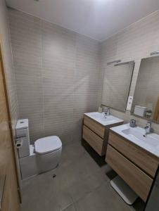 a bathroom with a toilet and two sinks and a mirror at Piso completo y moderno, Burgos in Burgos