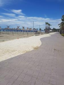 an empty beach with palm trees and umbrellas at Golem family lux apartment in Golem