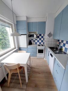 eine kleine Küche mit blauen Schränken und einem weißen Tisch in der Unterkunft Quiet studio - easy check-in, free parking & wifi in Rovaniemi