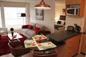 cocina y sala de estar con mesa y sofá en Concepción Suites, en Concepción