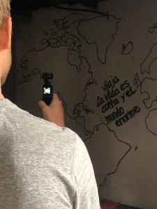 a man taking a picture of a world map on a wall at Cora Izone in Cob&aacute;n