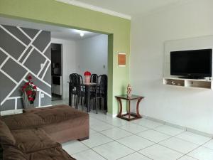 uma sala de estar com um sofá e uma televisão na parede em Um Paraíso no fim da rua em Barra de São Miguel