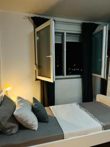 a bed with two pillows and a window in a room at Apartman Luna *** in Rijeka