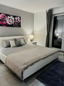 a white bedroom with a large bed and a window at Apartman Luna *** in Rijeka