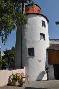 un bâtiment avec une tour dotée d'une fenêtre et d'un banc dans l'établissement YFB l 500 Jahre alter Stadtmauerturm, à Dillingen an der Donau