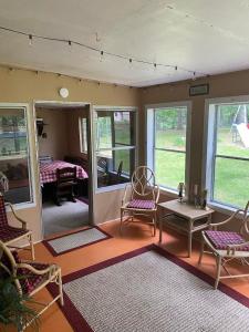 ein Wohnzimmer mit Stühlen, einem Tisch und Fenstern in der Unterkunft Maggie’s lil Cottage in Sampson