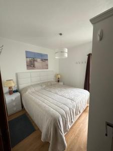a white bedroom with a large bed and a window at Sun Beach Apartment in Machico