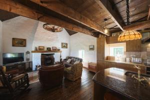 uma cozinha e sala de estar com um sofá e uma televisão em Maggie Deenys Cottage 