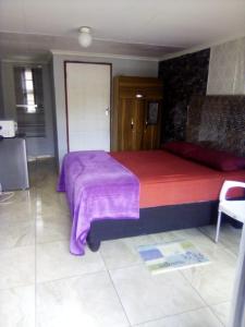 1 dormitorio con 1 cama grande con manta morada en Ecos platinum contractors B&B, en Northam