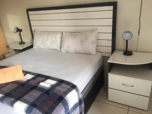 1 dormitorio con 1 cama y mesita de noche con lámpara en Ecos platinum contractors B&B, en Northam