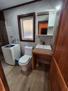 een badkamer met een toilet, een wastafel en een spiegel bij Casa Cochrane in Cochrane