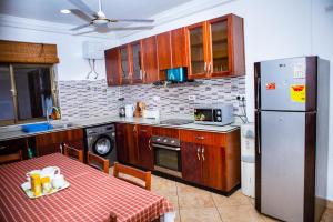 Il comprend une cuisine équipée d'une table et d'un réfrigérateur. dans l'établissement Luxor garden apartments, à Accra