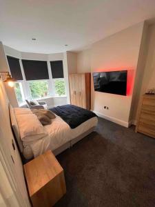 a bedroom with a bed and a flat screen tv at Modern 5 Bedroom Terraced Luxurious House in Colwyn Bay