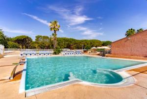 a large swimming pool with chairs and a palm tree at Mobilhome 6 personnes Camping Oasis Village 5 étoiles in Puget-sur Argens