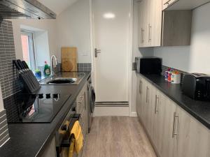 Cannock - 2 large bedroom house for work & leisure في Great Wyrley: مطبخ مع خزائن بيضاء وقمم منضدة سوداء