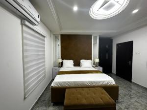 Un dormitorio con una cama grande y un banco. en KAIR Service Apartments, en Benin City