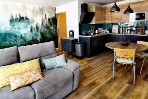 a living room with a couch and a kitchen at Proche Nancy centre, à quelques pas des Thermes et du campus ARTEM, appartement calme avec parking gratuit in Nancy