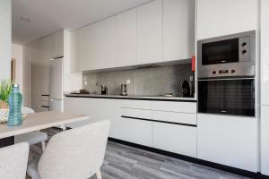 eine Küche mit weißen Schränken und einem Tisch mit Stühlen in der Unterkunft Blue Apartments in Leiria