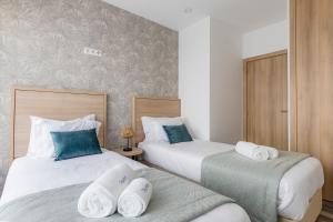 2 bedden in een hotelkamer met handdoeken bij Blue Apartments in Leiria