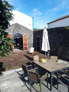 Ribeira das Tainhas的住宿－Quinta do Avô，一个带桌子和遮阳伞的庭院