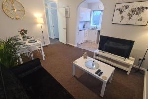 een woonkamer met een flatscreen-tv en een tafel bij An Idyllic Essex Escape in Witham