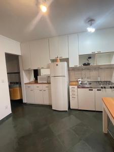 a kitchen with white cabinets and a white refrigerator at Piemonte Flat Serra Neg SP in Serra Negra