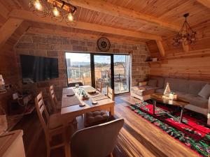 un salon avec une table, des chaises et une télévision dans l'établissement Guest House Max, à Žabljak