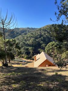 a barn in a field with a mountain in the background at Chalé Pinheiros da Mantiqueira in Camanducaia